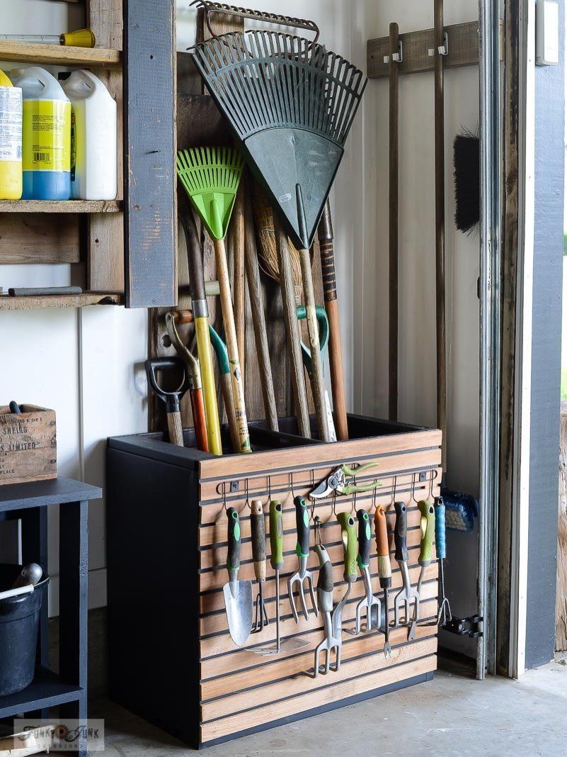Garage Storage for Lawn Equipment: 7 Ideas That Actually Fit 4 Wooden and black garden tool storage bin holding rakes, shovels, and hand tools.
