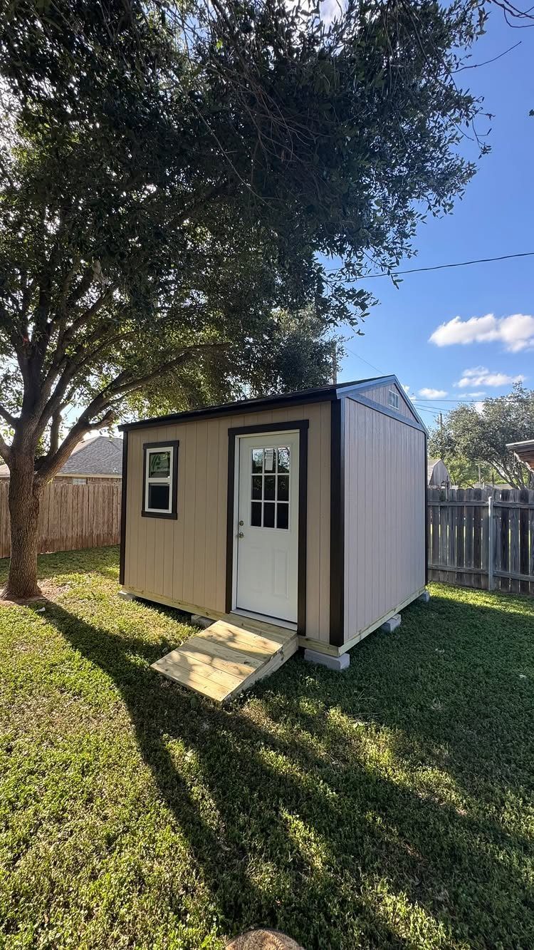Garage Storage for Lawn Equipment: 7 Ideas That Actually Fit 2 A tan outdoor storage shed with a white door sits on a green grass lawn.