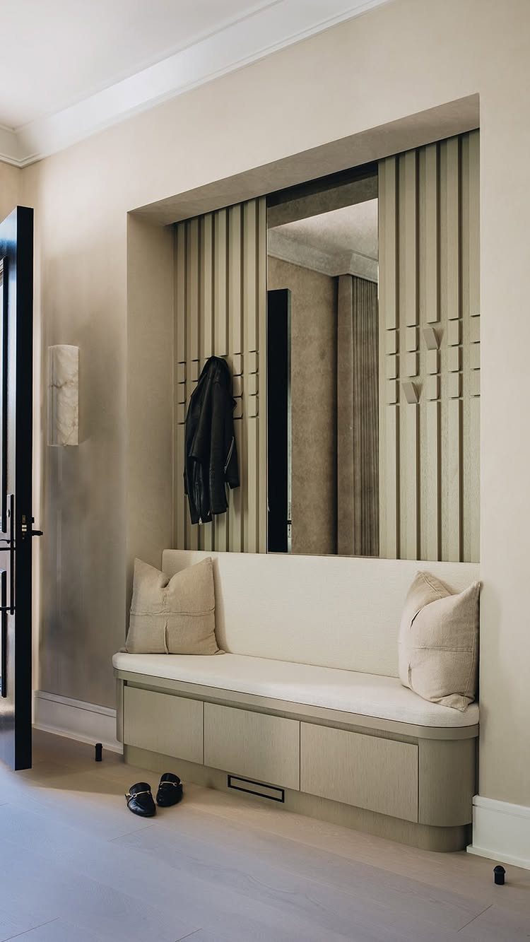 9 Hidden Storage Wall Ideas for a Cleaner Home 5 A built-in entryway bench with a vertical slat wall and a hanging black jacket.