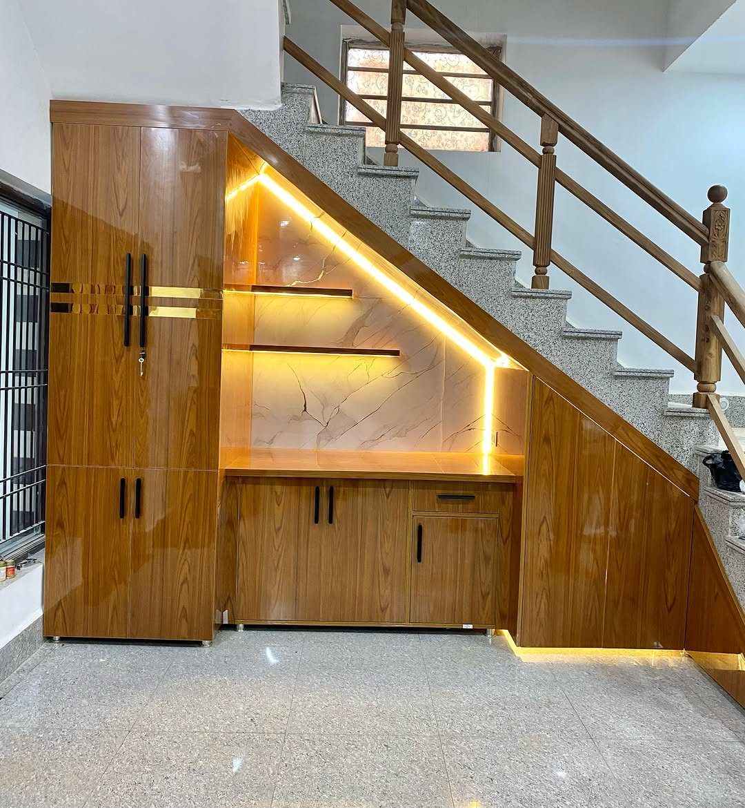 9 Hidden Storage Wall Ideas for a Cleaner Home 2 Wooden storage cabinets and lit shelving units built into the space under a staircase.