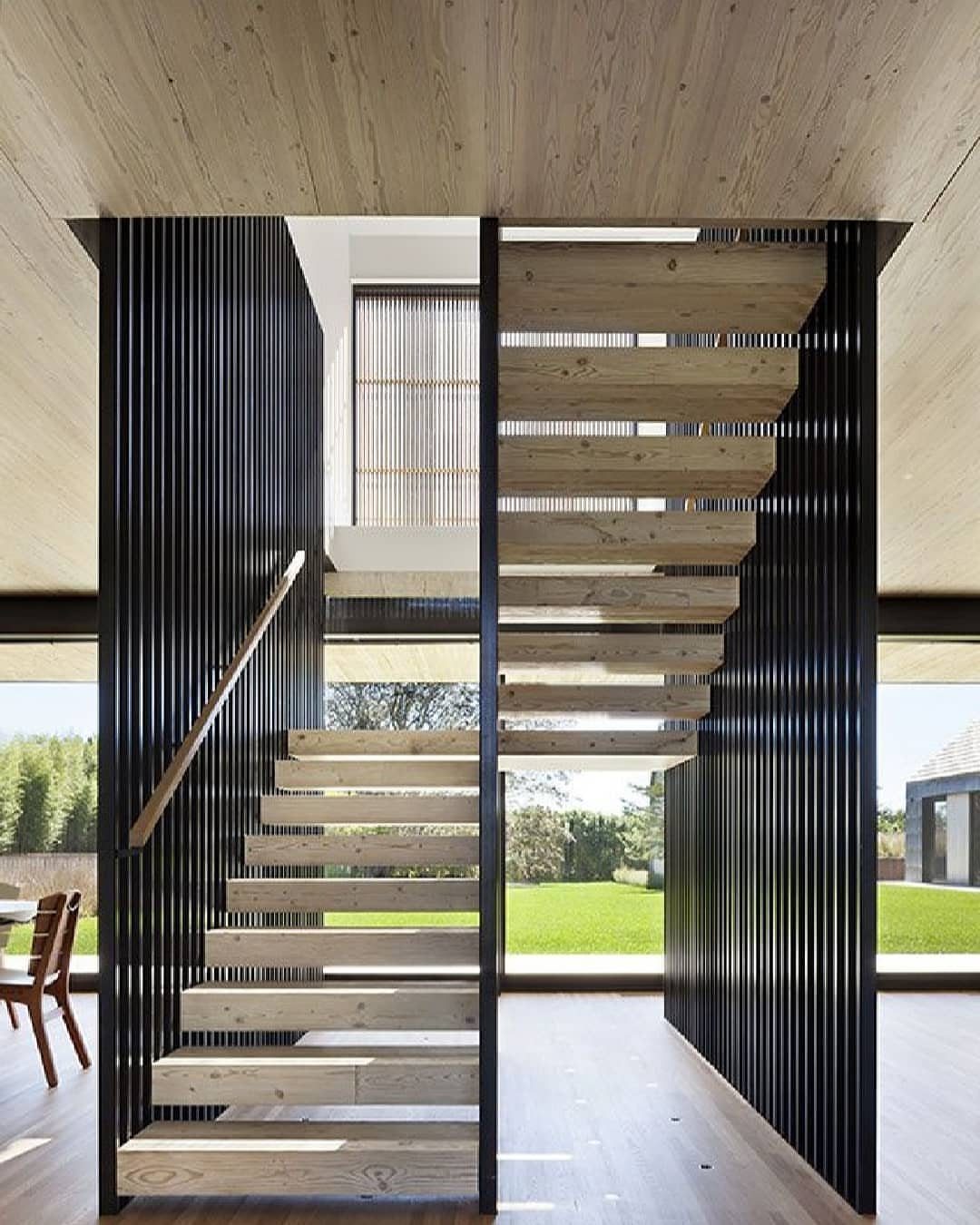 Home Stairs Design: 12 Ideas from Glass Treads to Built-In Storage 4 Floating wooden stair treads suspended against a black slatted wall in a modern bright home.