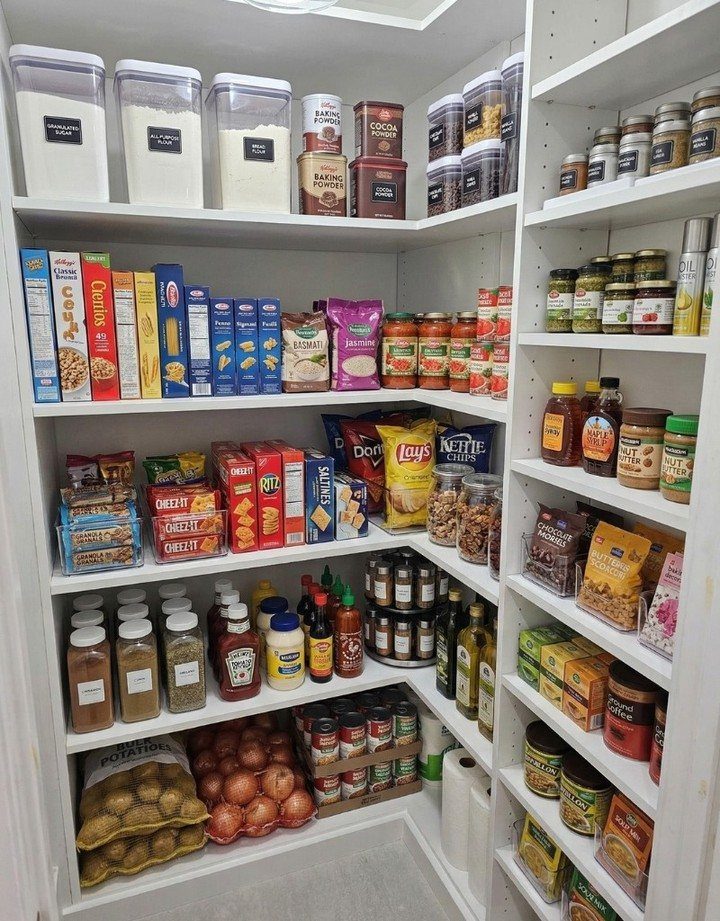 A white pantry shelf filled with organized food containers, snacks, jars, and bags of vegetables.