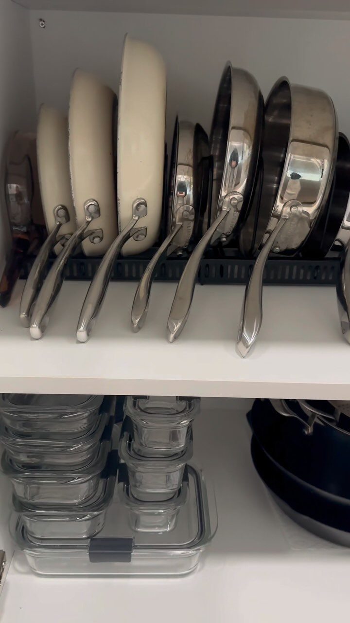 9 Kitchen Tools Organization Ideas for Cabinets, Drawers & Walls 10 Frying pans organized vertically in a black wire rack inside a white kitchen cabinet.