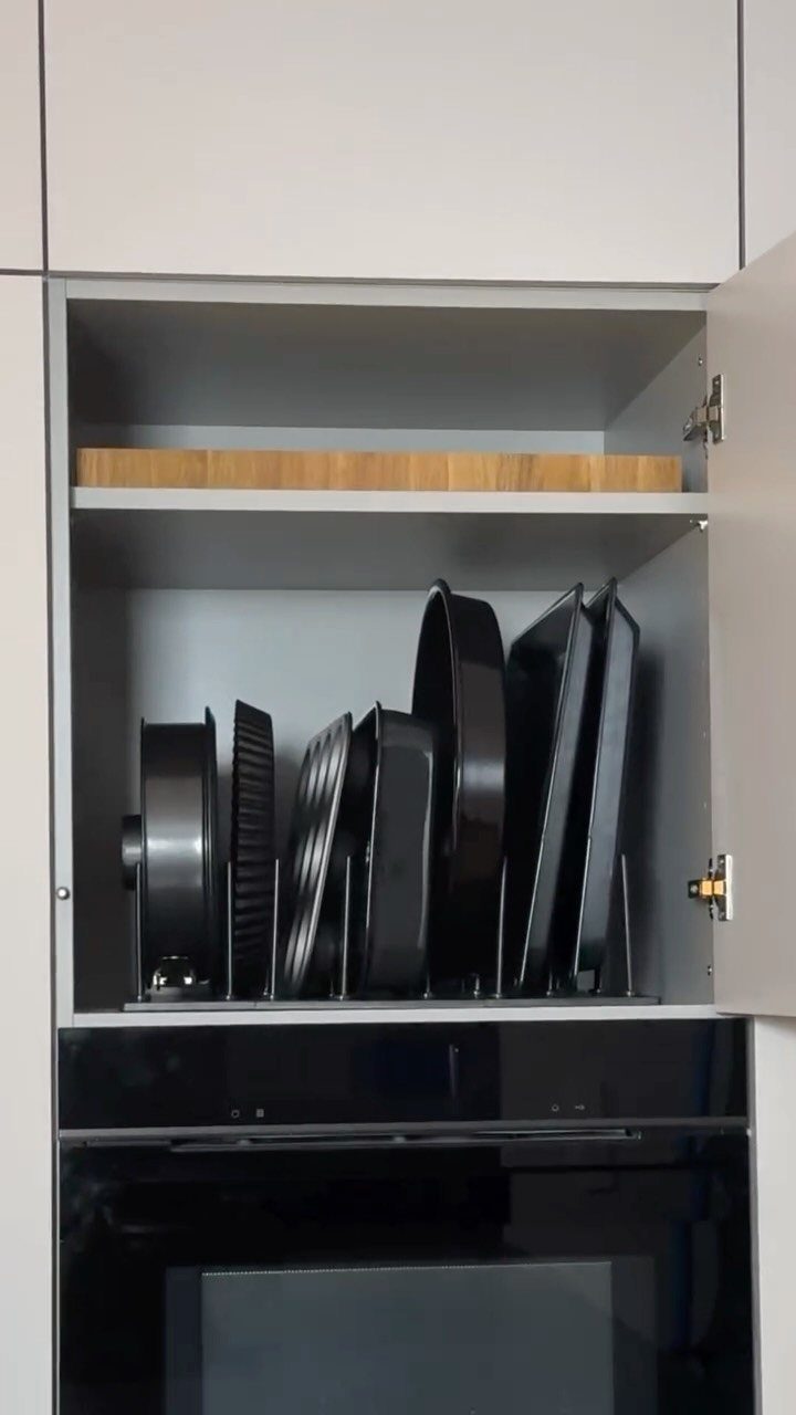 9 Kitchen Tools Organization Ideas for Cabinets, Drawers & Walls 2 Black baking sheets stored vertically in a grey kitchen cabinet using metal dividers.