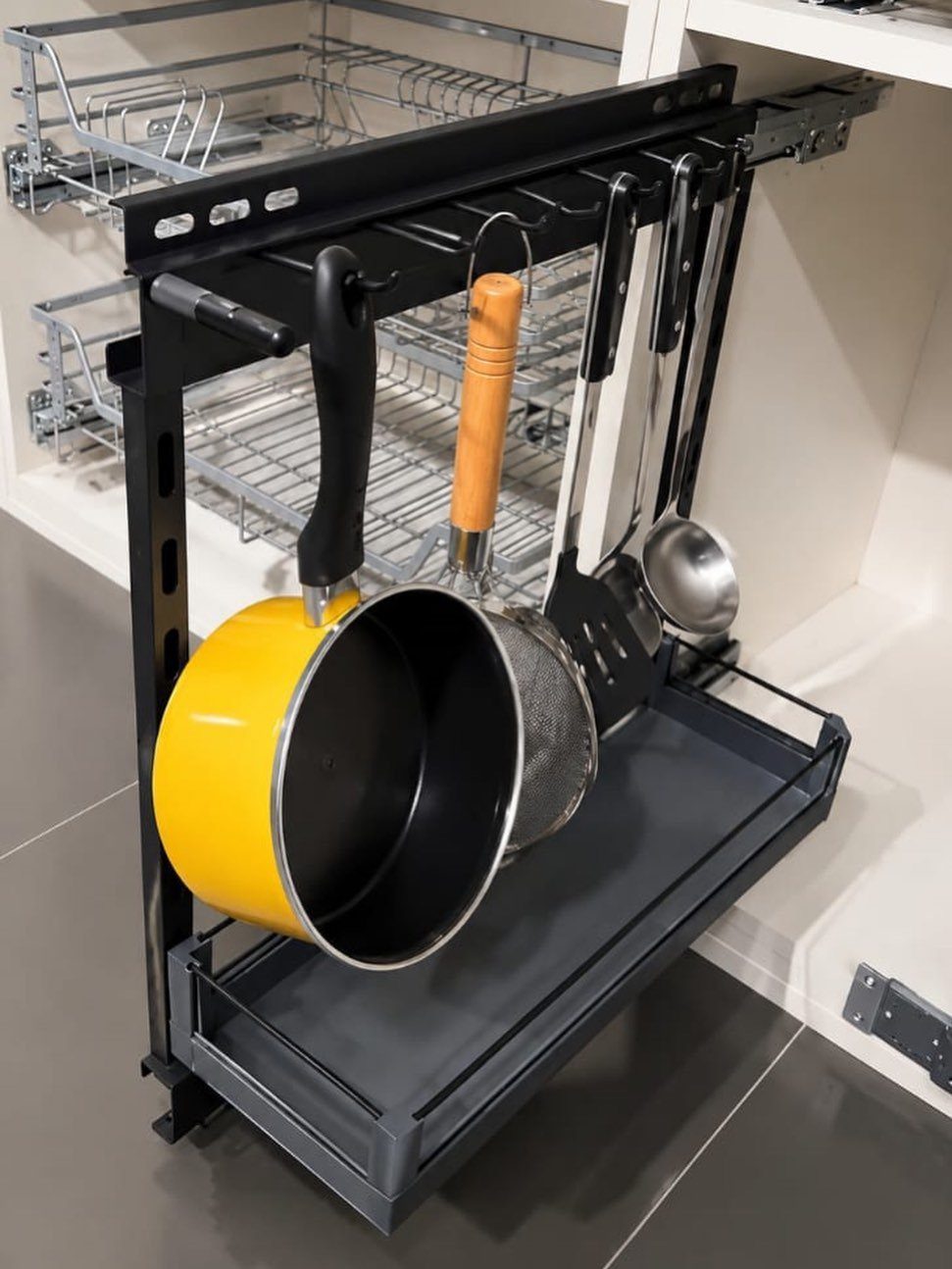 9 Kitchen Tools Organization Ideas for Cabinets, Drawers & Walls 8 A black pull-out kitchen organizer rack holding a yellow pot and various metal cooking utensils.