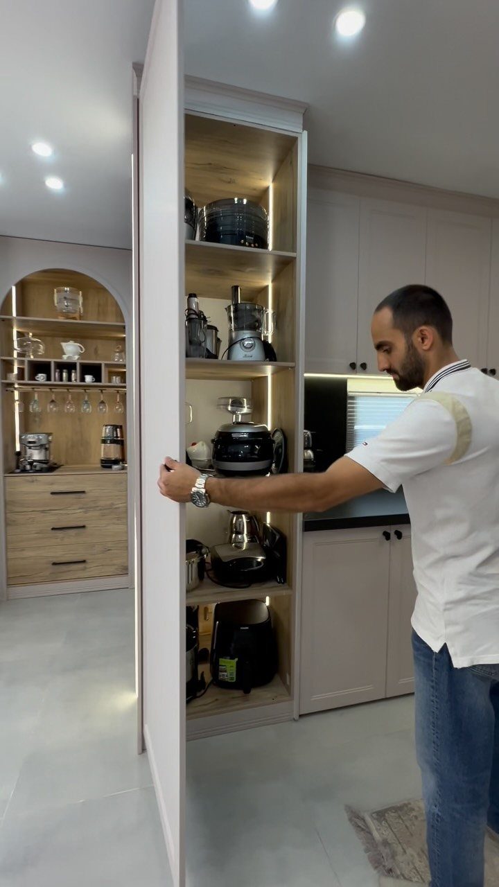 Kitchen with Hidden Pantry: 8 Ideas That Blend Right In 8 A man opening a tall, narrow pantry cabinet filled with various kitchen appliances.