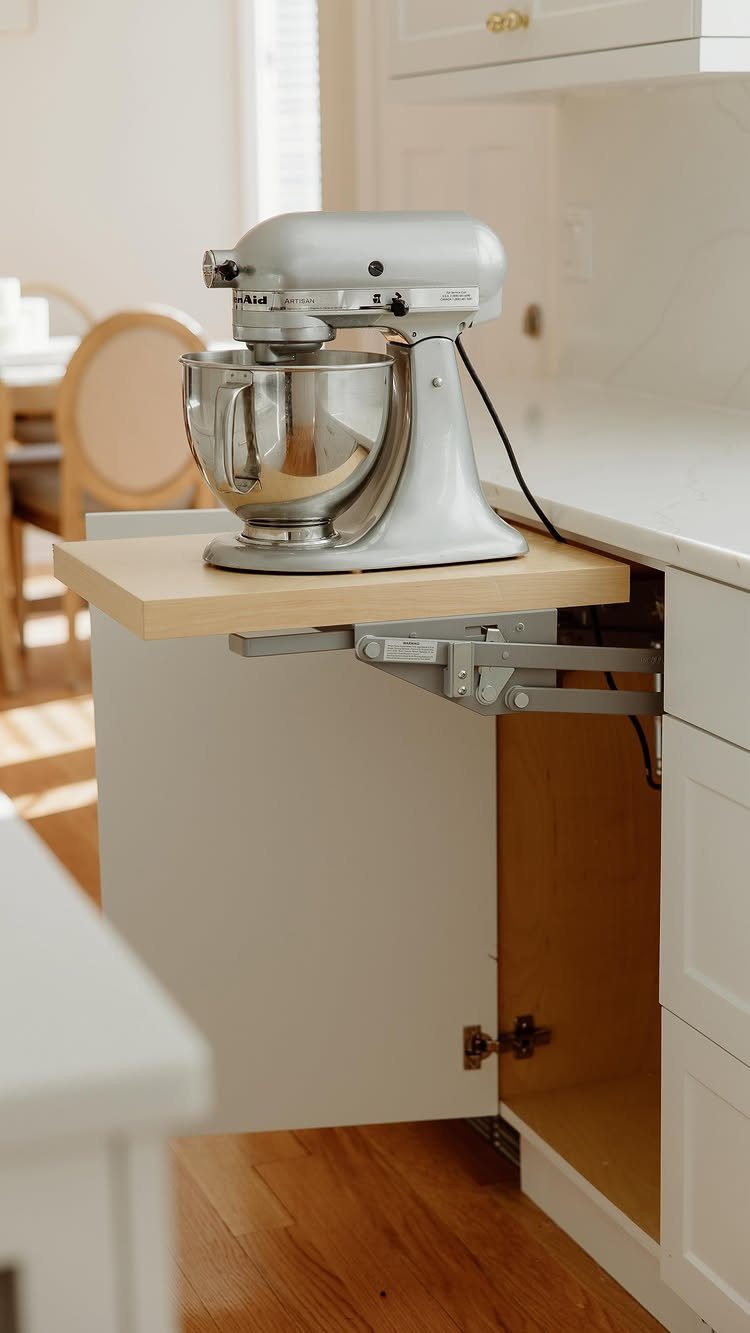 Kitchen with Hidden Pantry: 8 Ideas That Blend Right In 3 A silver stand mixer on a wooden pull-out shelf extended from a white kitchen cabinet.