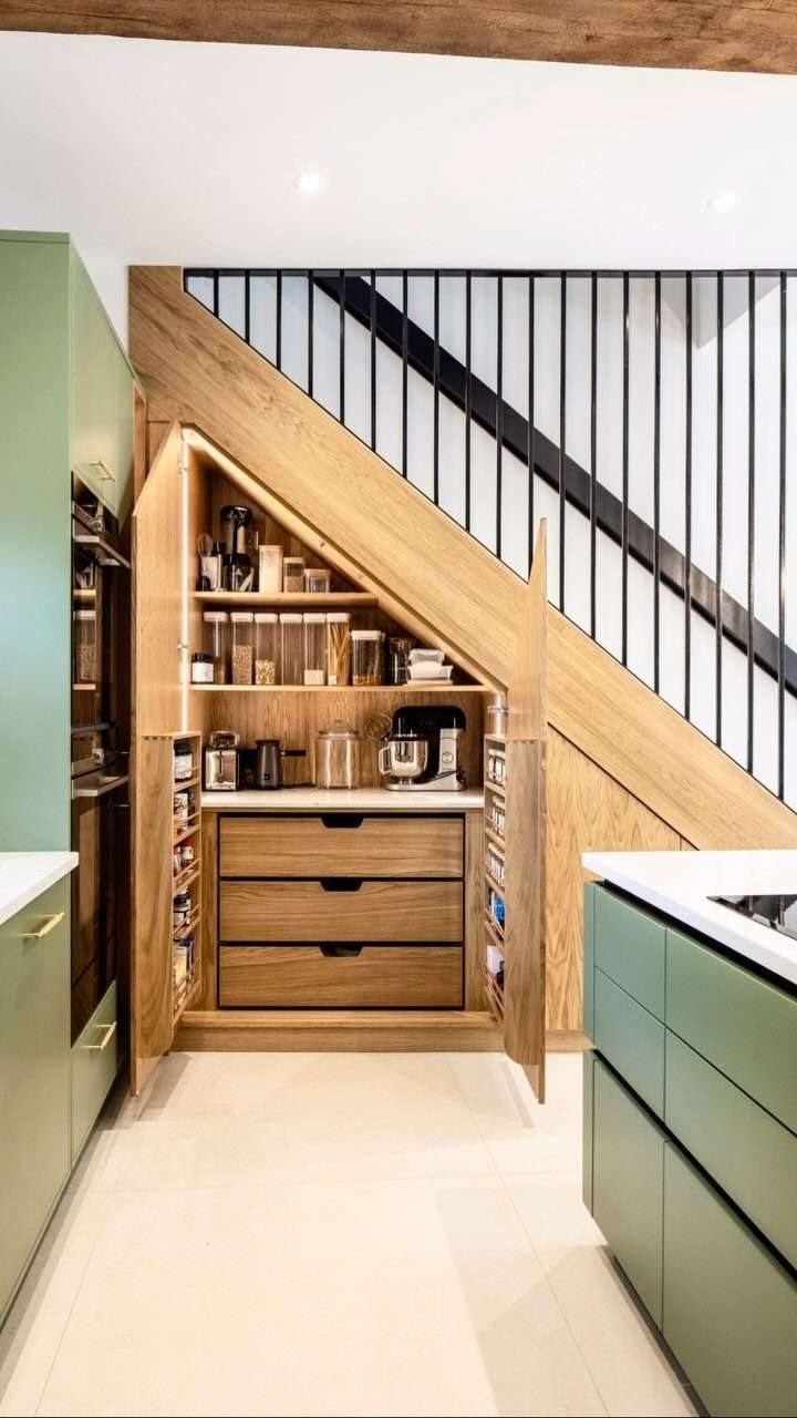 Kitchen with Hidden Pantry: 8 Ideas That Blend Right In 4 A wooden pantry with shelves and drawers built into the space under a staircase.