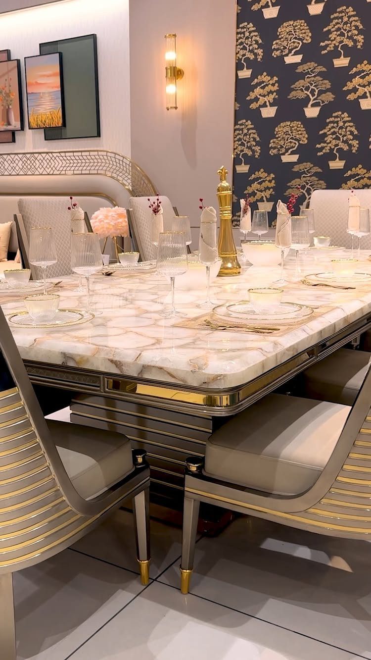 A large marble dining table with gold accents set in a modern dining room.