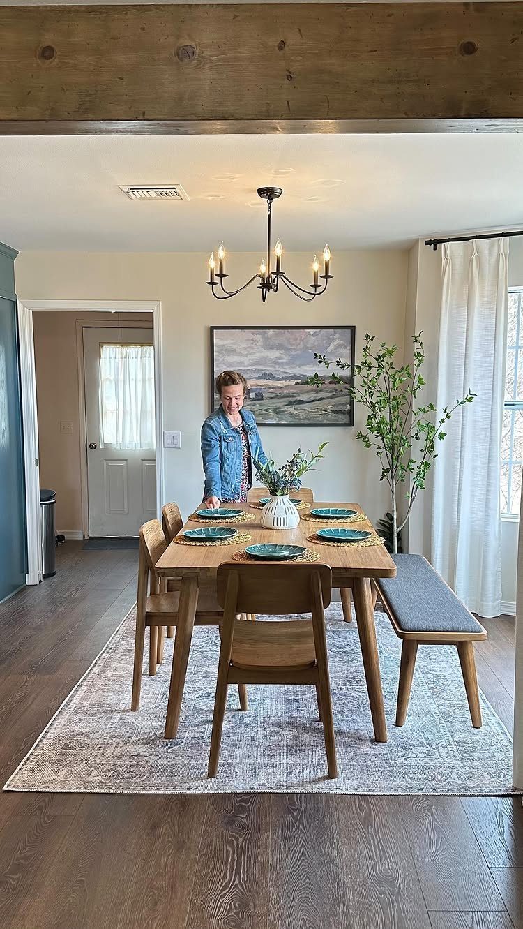 A wooden dining set with a bench sits on a large patterned area rug.