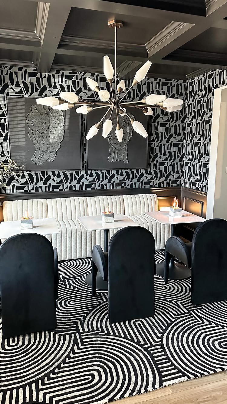 Black and white patterned wallpaper and rug in a modern dining room setting.