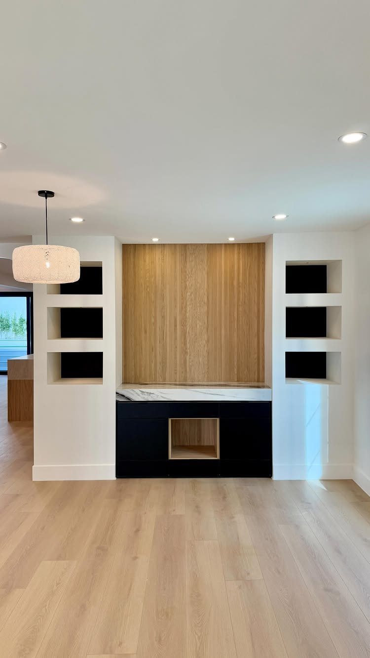 Built-in cabinetry with wood paneling, black lower cabinets, marble countertop, and recessed shelving niches.