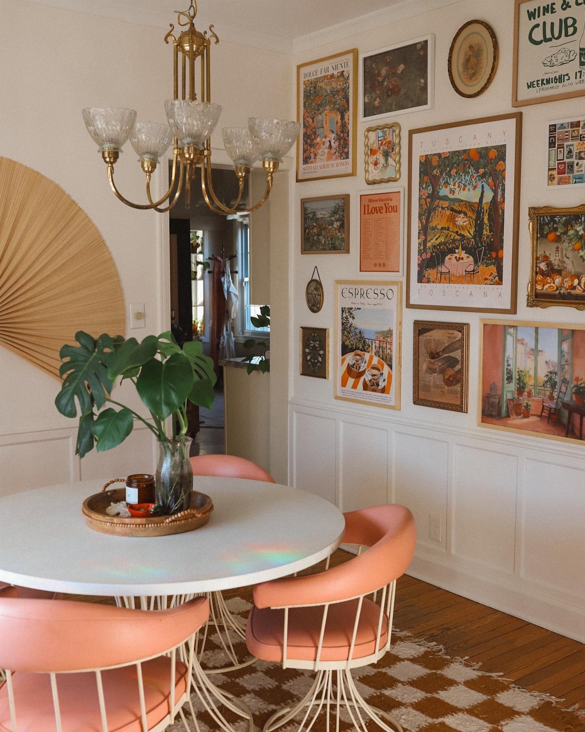 A dining room set with pink chairs and a large gallery wall of framed art.