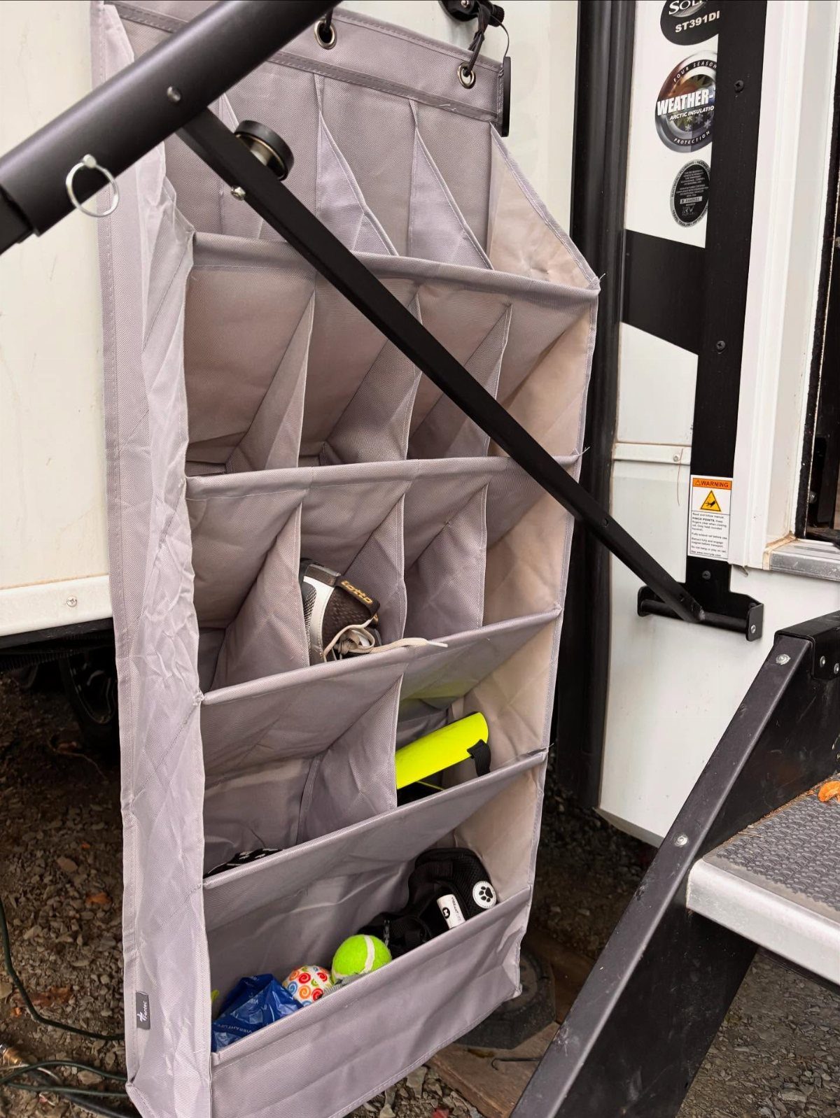 RV Shoe Storage: 6 Ideas That Save Space and Sanity 7 A grey hanging fabric organizer with pockets containing shoes attached to the side of an RV.