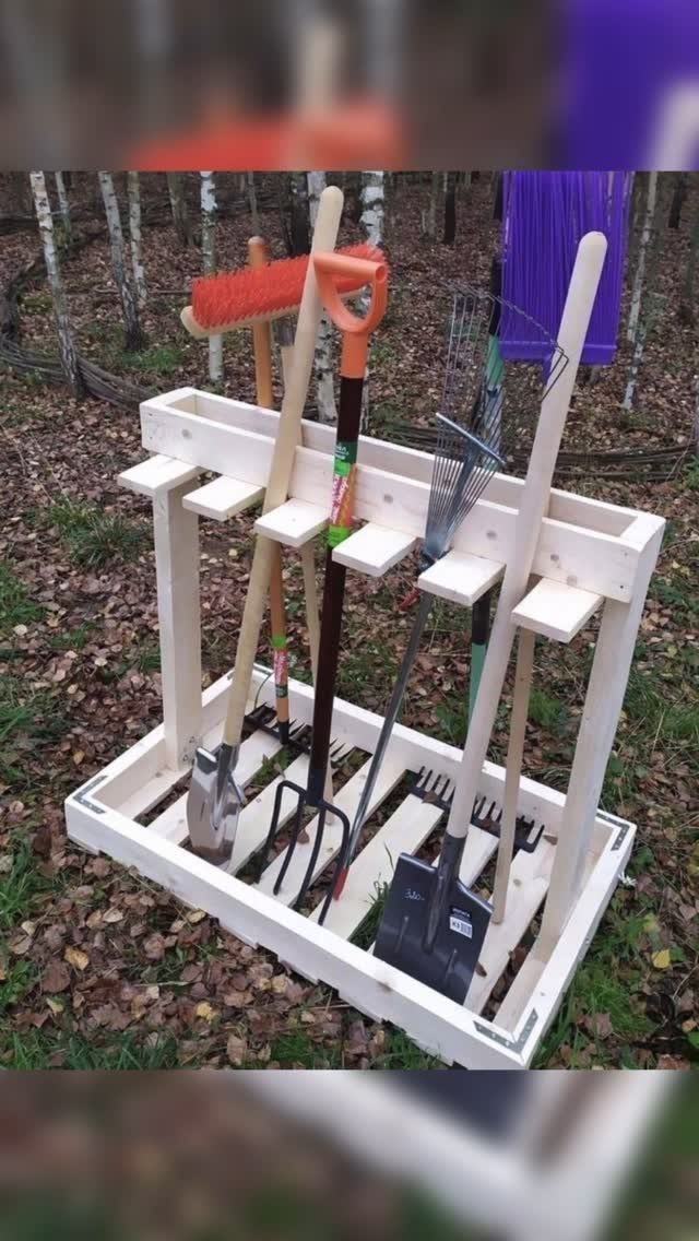 14 Shed Organization Ideas for a Tidy, Functional Space 13 A wooden garden tool organizer holding a shovel, rake, and pitchfork on a bed of leaves.