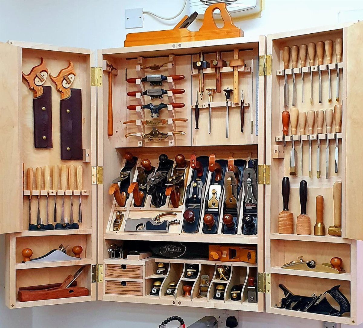13 Shop Tool Storage Ideas for Pegboard, Carts and Cabinets 9 An open wooden tool cabinet filled with organized woodworking tools and hand planes.