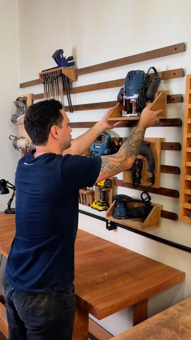 13 Shop Tool Storage Ideas for Pegboard, Carts and Cabinets 5 A man organizes power tools on a wooden wall storage rack system in a workshop.