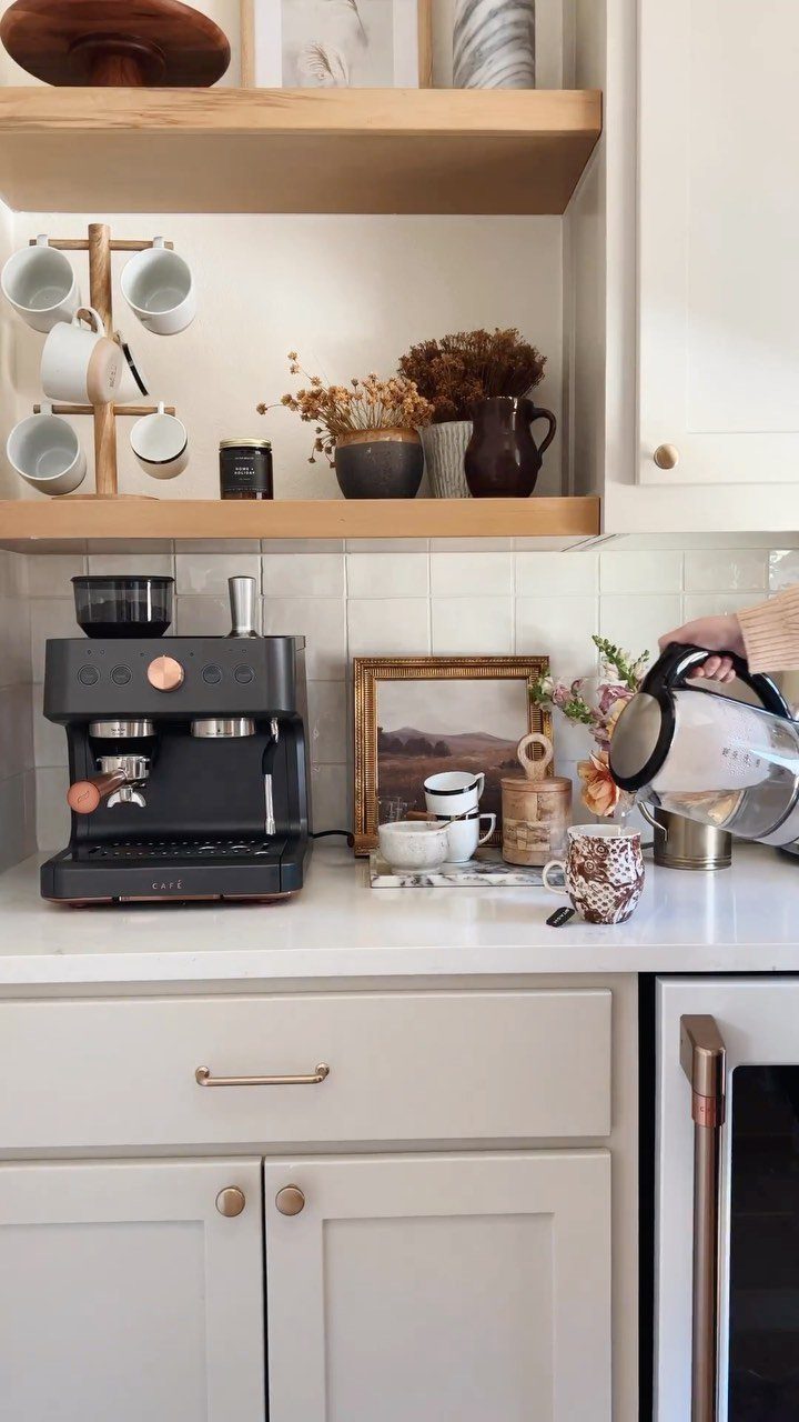 18 Small Kitchen Remodel Ideas to Open Up Your Space 19 A black espresso machine and coffee mugs arranged on a white kitchen countertop.