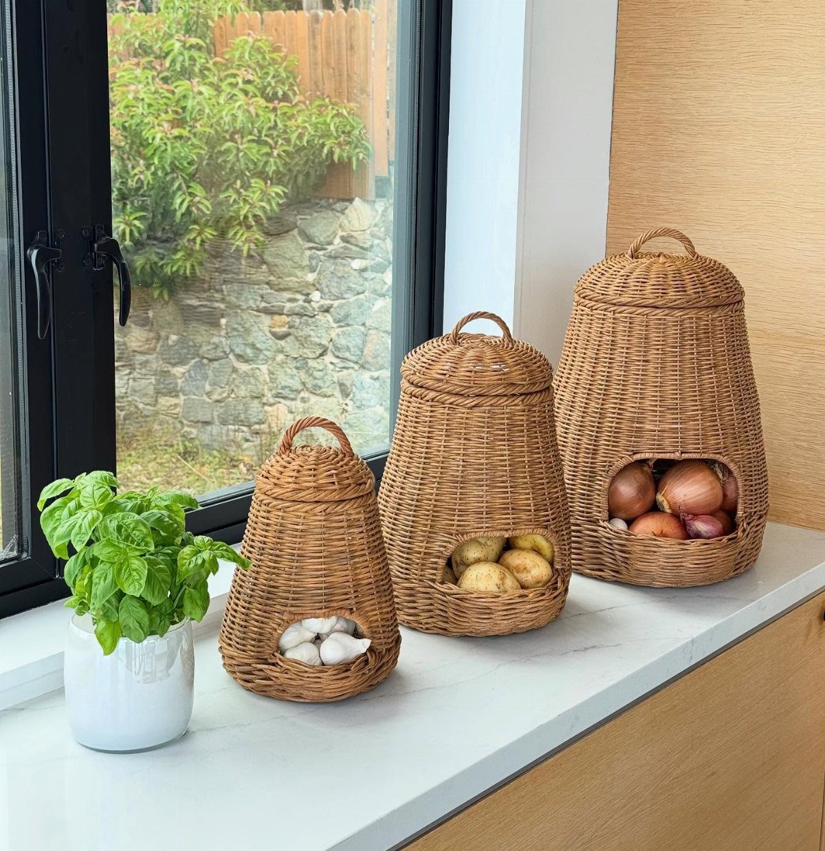 18 Small Kitchen Remodel Ideas to Open Up Your Space 18 Three woven wicker baskets containing garlic, potatoes, and onions sit on a white kitchen countertop.