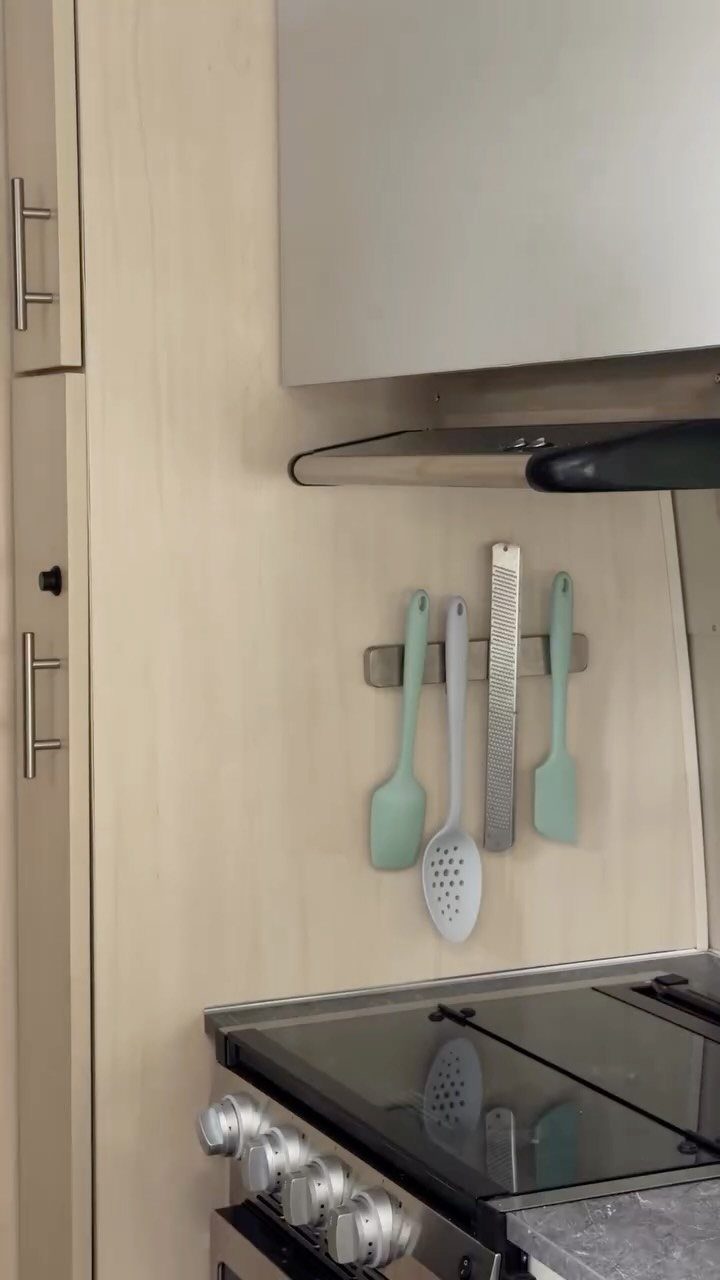 18 Small Kitchen Remodel Ideas to Open Up Your Space 16 Magnetic strip on a kitchen backsplash holding a spatula, slotted spoon, and grater.