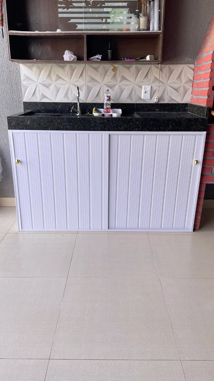 18 Small Kitchen Remodel Ideas to Open Up Your Space 13 White vertical-slatted sliding cabinet doors under a black kitchen countertop with a sink.