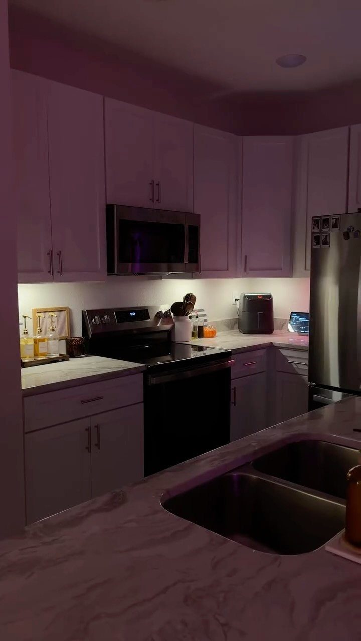 18 Small Kitchen Remodel Ideas to Open Up Your Space 3 White kitchen cabinets with warm under-cabinet lighting illuminating the countertop and backsplash area.