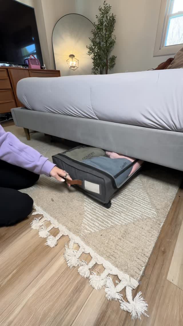 12 Storage Ideas for Small Homes to Add Extra Space Fast 3 A person reaching for a grey fabric storage bin tucked under a grey bed frame.