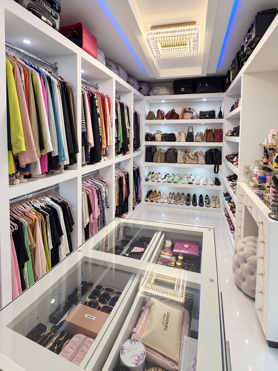 Walk in Closet Storage: 9 Ideas That Work in Real Homes 5 Organized white walk-in closet with color-coordinated clothing, handbags, and shoes on shelves.