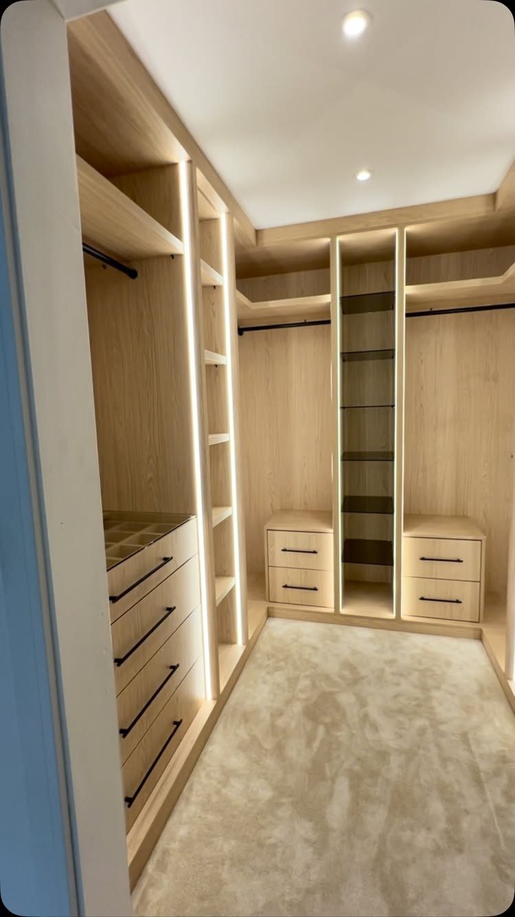 Walk in Closet Storage: 9 Ideas That Work in Real Homes 8 Light wood walk-in closet featuring built-in drawers, hanging rods, and integrated LED strip lighting.