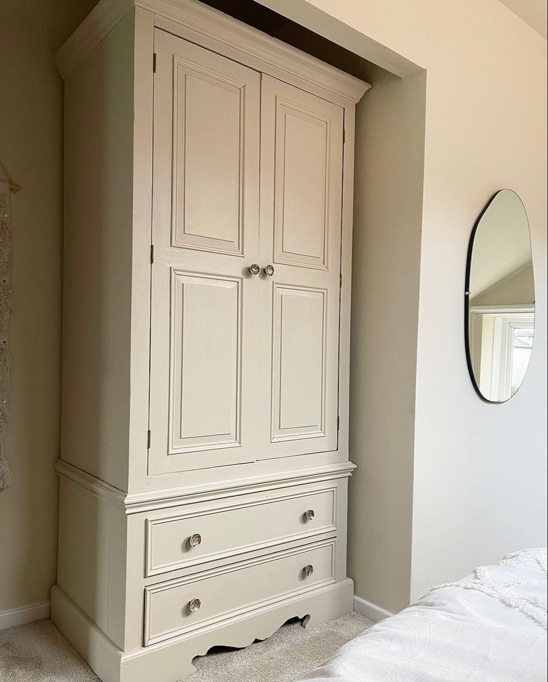14 Wardrobe Interior Design Ideas for Every Bedroom 8 Cream freestanding wardrobe with two doors and two drawers standing in a neutral bedroom.