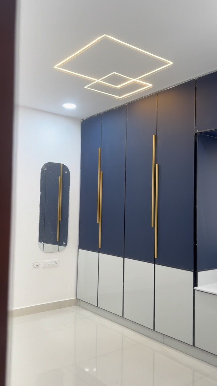 14 Wardrobe Interior Design Ideas for Every Bedroom 10 Navy blue and white wardrobe with long gold handles in a bright room.